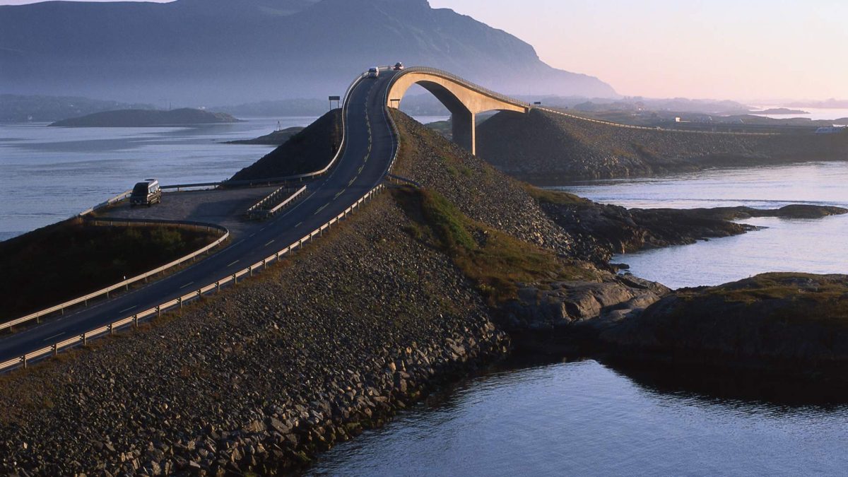 Motorcycle riding famous Atlantic Ocean Road Norway Storseisundet curved bridge connecting islands dramatic Norwegian coastal scenery guided tour