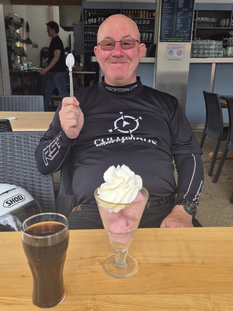 Man eating an ice cream sunday with a motorcycle t shirt on
