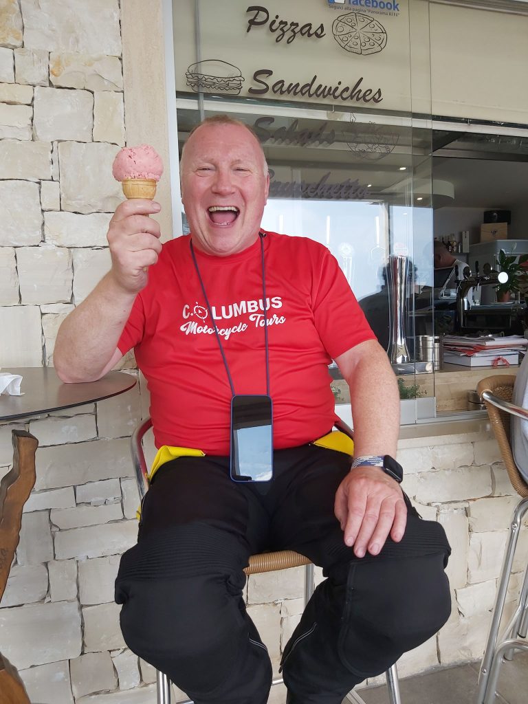 Man eating an ice cream cone with a red motorcycle t shirt on