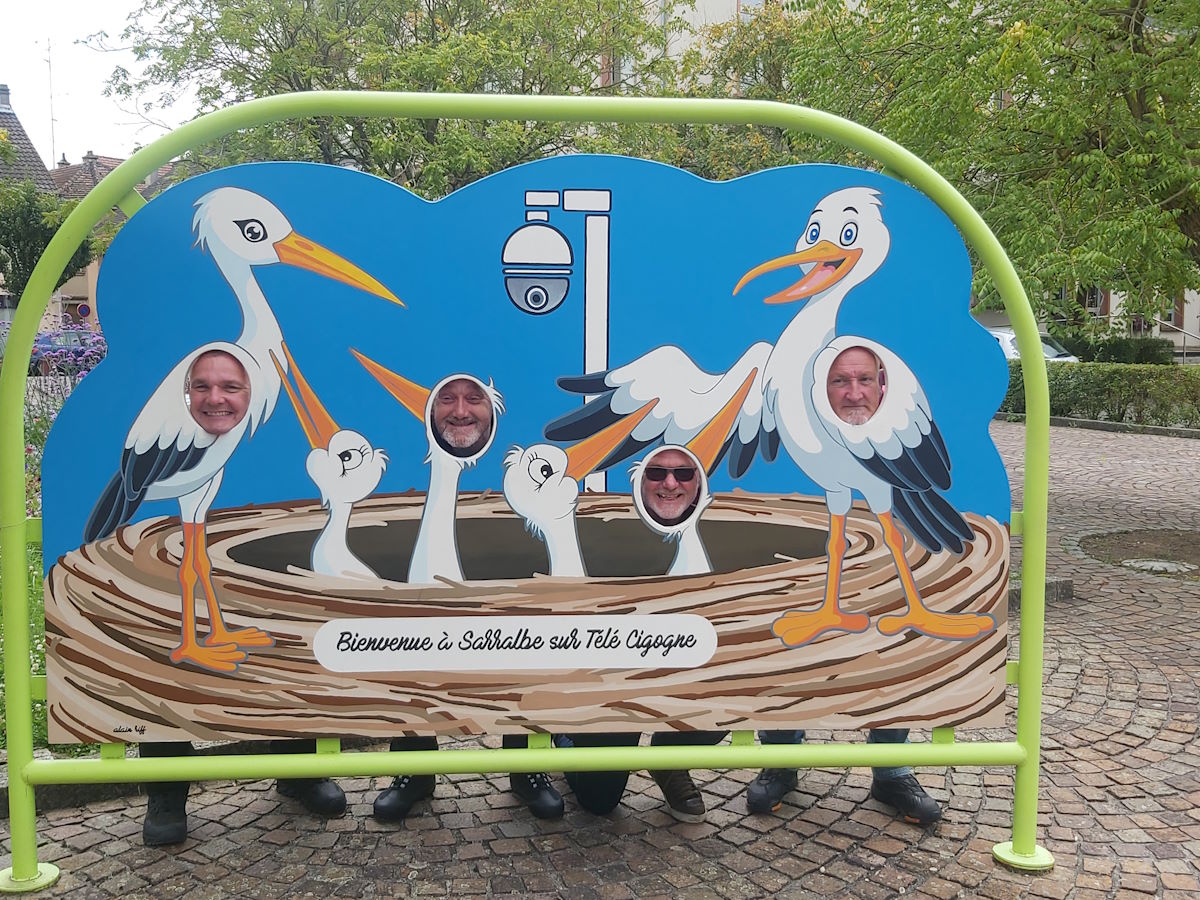 Tour members fun photo stork cutout board Sarralbe sur Tete Cigogne Alsace village France motorcycle tour 2024