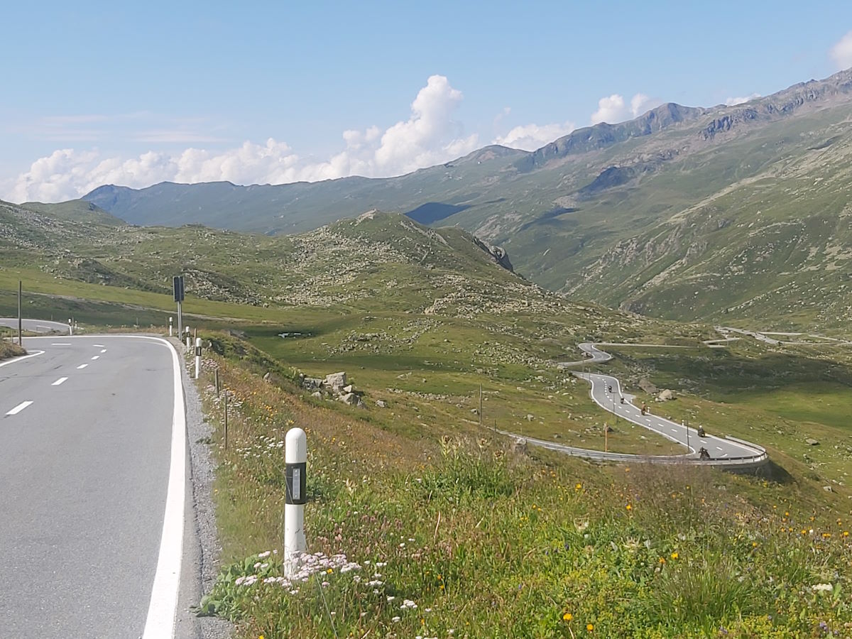 Columbus Motorcycle group descending Fluela Pass sweeping hairpin bends Alpine meadows Switzerland Austrian Swiss Alps tour 2024