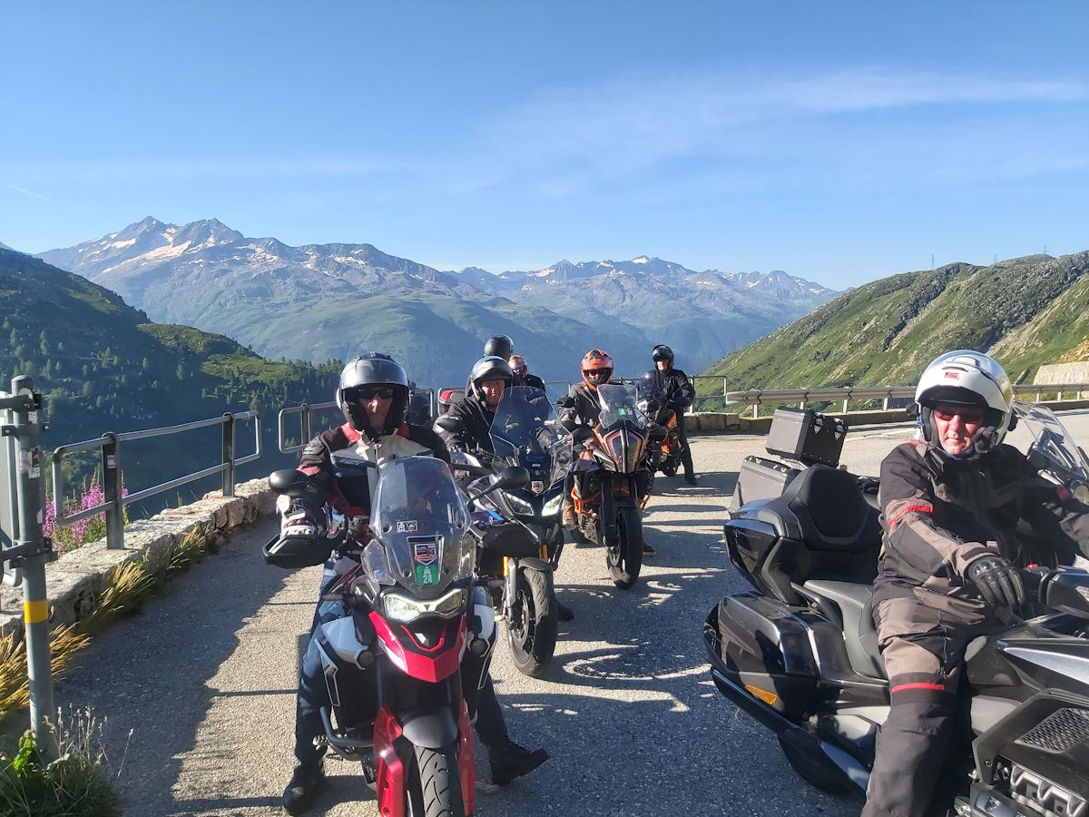 Columbus Motorcycle Tours group Grimsel Pass Alpine peaks background Austrian Swiss Alps tour August 2024